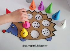 a child's hand is playing with numbers and shapes on a hedgehog craft