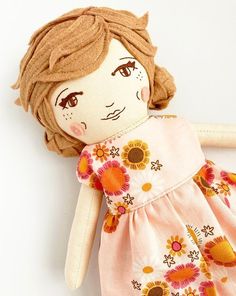 the doll is wearing a pink dress with sunflowers on it's chest