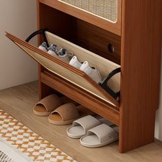 an open shoe rack with two pairs of slippers and shoes on the floor next to it