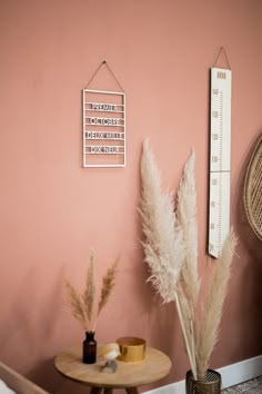 a room with pink walls and some plants in vases next to a wooden table