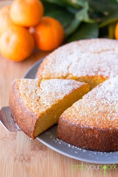 a cake that is sitting on a plate with some oranges in the back ground