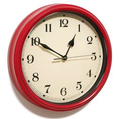 a red clock with black hands and numbers on it's face is seen against a white background