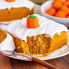 a slice of pumpkin cake with white frosting on a plate next to carrots