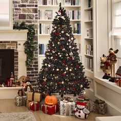 a decorated christmas tree in front of a fireplace with presents on the floor next to it