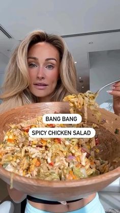 a woman holding a wooden bowl full of food with the caption bang bang spicy chicken salad