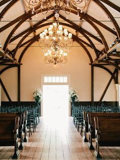 the inside of a church with chandeliers and pews in front of it