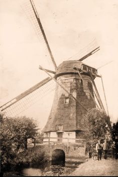 an old black and white photo of people standing in front of a windmill that has been built