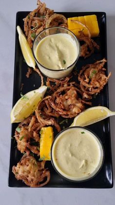 a black plate topped with fried food and dipping sauce