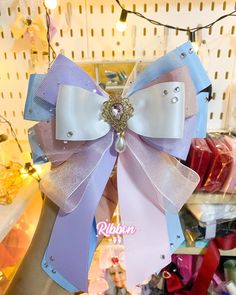 a large purple and white bow with pearls on it's end, hanging from the ceiling