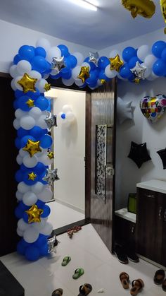 blue and white balloon arch with gold stars on it in a room filled with balloons