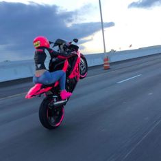 a person riding a pink motorcycle on a highway