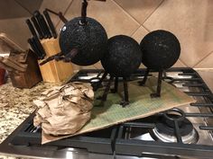 three black balls sitting on top of a stove next to a cutting board and utensils