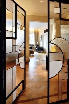 an open door leading into a living room with wood floors and glass panels on the doors