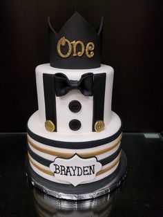 a three tiered cake decorated with black and white stripes, gold accents and a crown