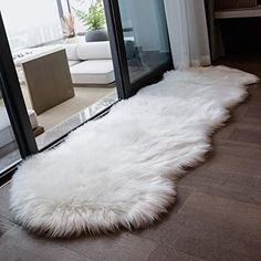 a white sheepskin rug on the floor in front of a sliding glass door