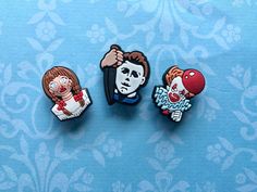 three pin badges depicting the faces of people with different facial expressions