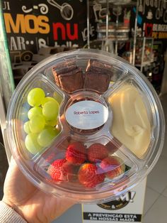 a person holding up a plastic container with food in it's center and fruit on the other side