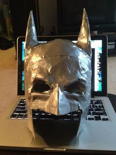 a laptop computer with a batman mask on it's face sitting on a table