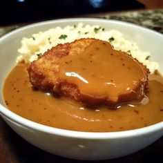 a white bowl filled with mashed potatoes covered in gravy