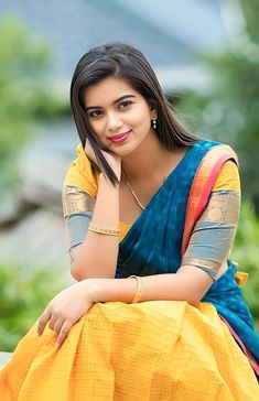 a woman sitting on top of a bench wearing a yellow and blue sari dress