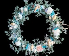 a wreath with seashells and seaweed is shown on a black background in this image