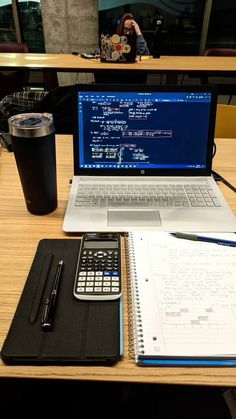 an open laptop computer sitting on top of a desk next to a calculator