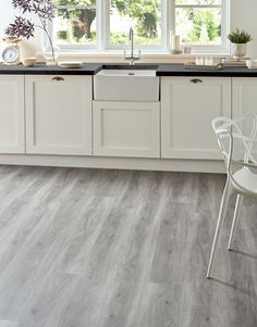 a kitchen with white cabinets and gray flooring