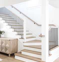 a living room filled with furniture and a stair case next to a white couch on top of a hard wood floor