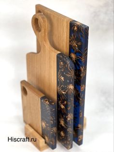 a wooden cutting board with blue and gold designs on it's sides next to a knife block