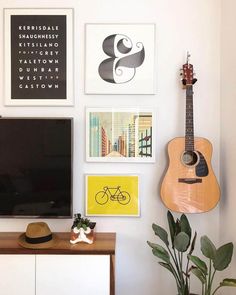 a living room with pictures and a guitar hanging on the wall next to a tv