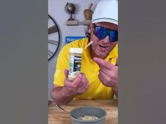 a man in yellow shirt eating cereal from a bowl with blue sunglasses on his face