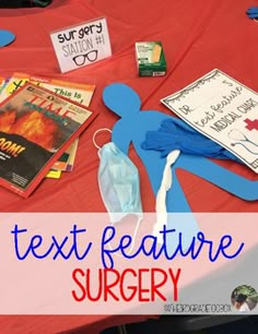 a table topped with books and toys on top of a red cloth covered tablecloth