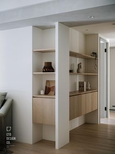 a living room filled with furniture next to a wall mounted book shelf on top of a hard wood floor