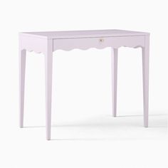 a small white table with scalloped legs and a drawer on the bottom shelf