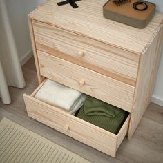 an open drawer in a wooden cabinet next to a rug and towel dispenser