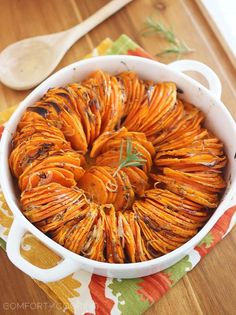 a casserole dish filled with cooked sweet potatoes and garnished with herbs