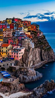 the colorful buildings are perched on top of the cliff above the water's edge