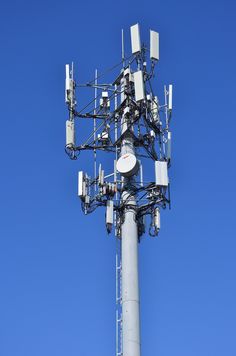 a tall white tower with many antennas on it's sides against a blue sky