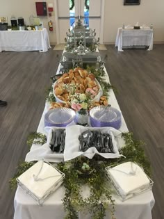 a long table covered with lots of food and drinks on top of white clothed tables