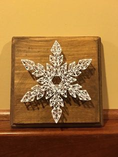 a snowflake made out of string on top of a wooden box