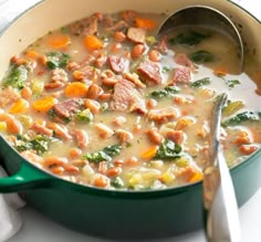 a green pot filled with soup on top of a white tablecloth next to a silver spoon