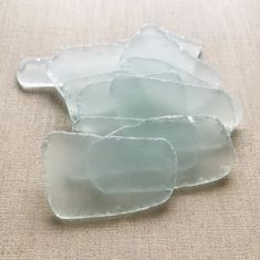 several pieces of sea glass sitting on top of a beige cloth covered tablecloth,