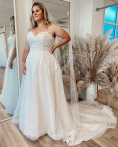 a woman standing in front of a mirror wearing a wedding dress