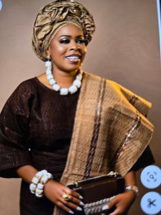 an african woman in a brown dress holding a purse and smiling at the camera with her hands on her hips