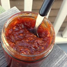 a jar filled with sauce sitting on top of a wooden table