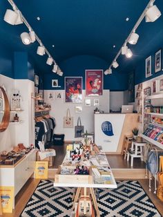 the inside of a clothing store with lots of items on tables and lamps hanging from the ceiling