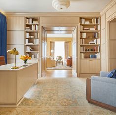 a living room filled with furniture and bookshelves next to a doorway that leads to a sitting area