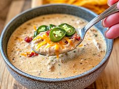 a hand holding a spoon full of quesadilla soup with cheese and jalapenos