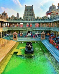 a boat is in the middle of a green pond with people standing on either side