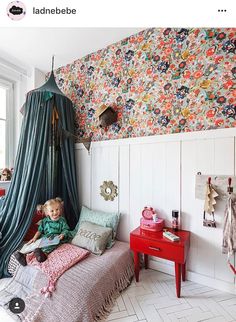 a bedroom with floral wallpaper and colorful bedding on the walls, along with a canopy